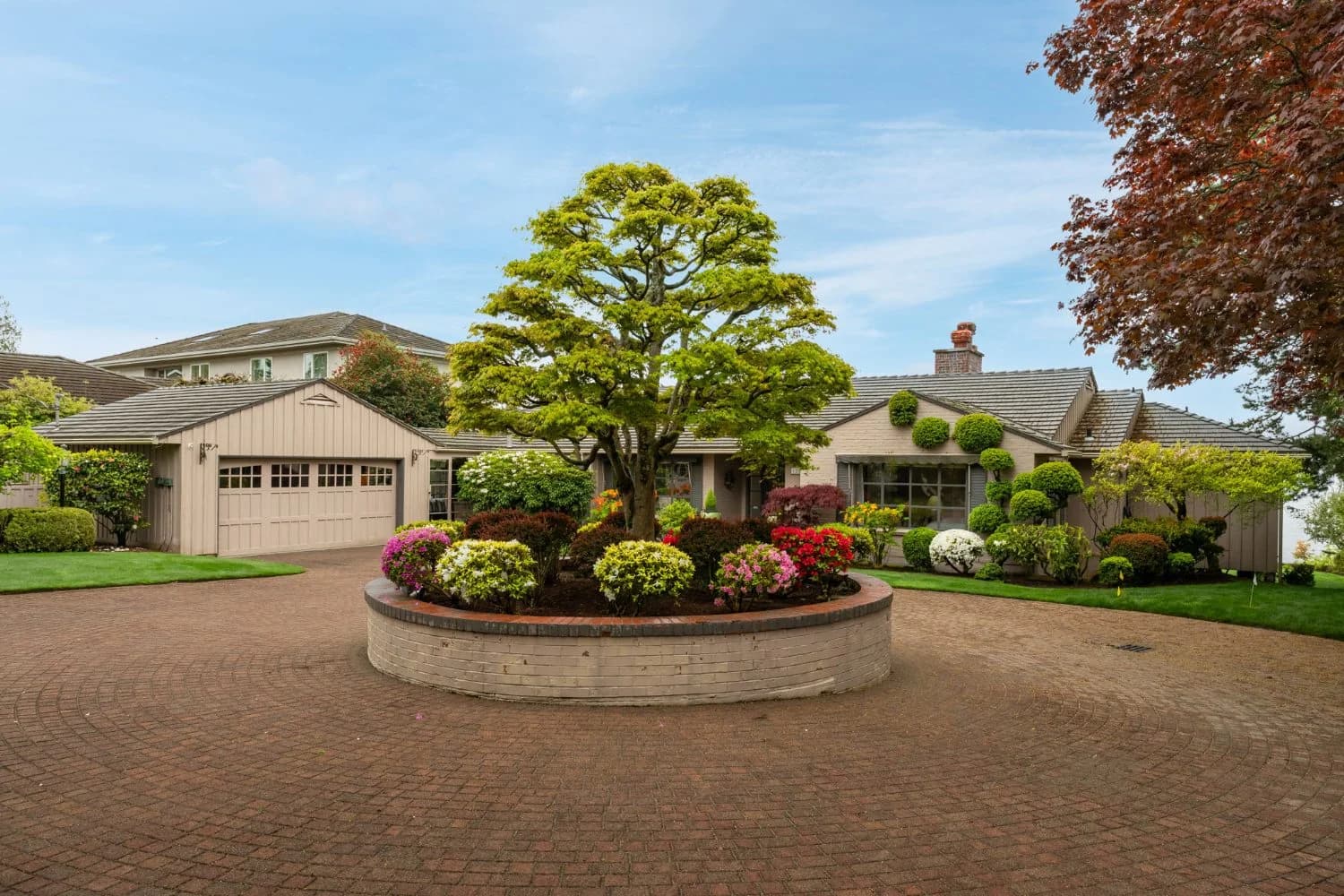A Pacific Northwest home with a brick circular drive and a planted center island, the opening photograph of the page for sellers